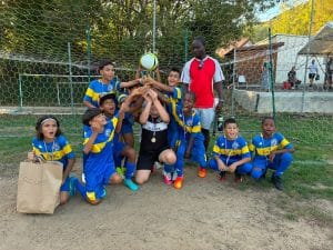 Équipe en maillot bleu et jaune brandissant le ballon devant le but