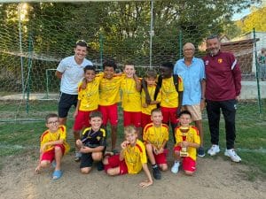 Équipe du FC Plateau 39 en maillot jaune et rouge entourée de ses éducateurs