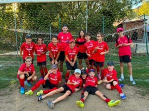 Équipe en maillot rouge posant assise devant le but
