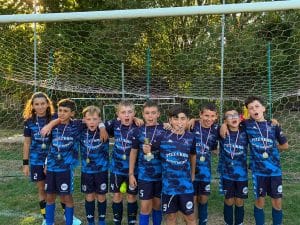 Jeunes joueurs en maillot bleu posant avec leurs médailles