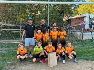 Équipe en maillot orange posant avec ses deux éducateurs